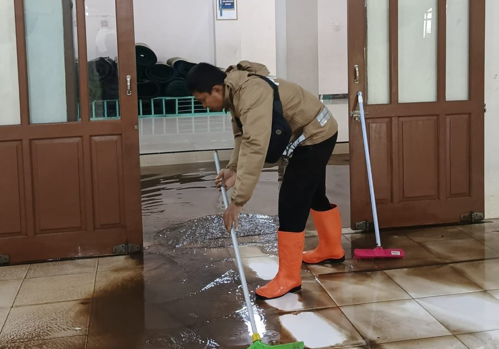 Bhabinkamtibmas, pengurus masjid, dan warga setempat bahu-membahu membersihkan area masjid dari lumpur,