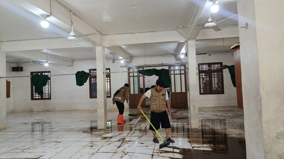 Bhabinkamtibmas, pengurus masjid, dan warga setempat bahu-membahu membersihkan area masjid dari lumpur,